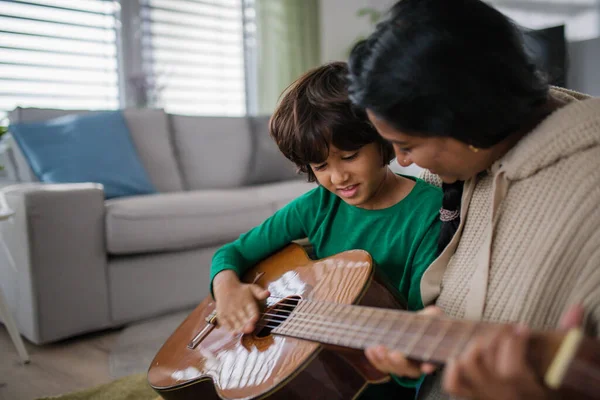 Küçük çok kültürlü çocuk evde annesiyle gitar çalmayı öğreniyor.. — Stok fotoğraf