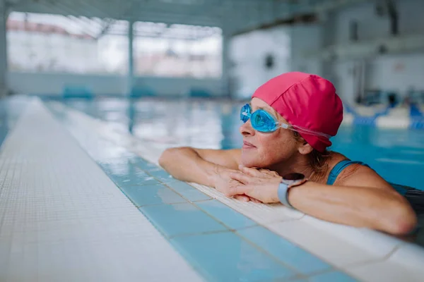 Gelukkig senior vrouw in het zwembad, leunend op rand. — Stockfoto