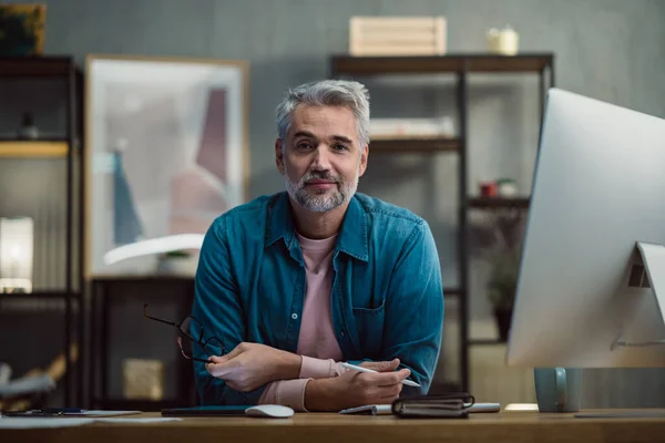 Mature man architect working on tablet at desk indoors in office, looking at camera. — Stock Photo, Image