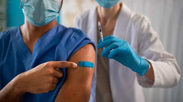 Närbild av oigenkännlig läkare som visar bandage på armen efter vaccinering. — Stockfoto