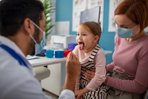 Ung manlig läkare kollar små flickor hals på sitt kontor. — Stockfoto