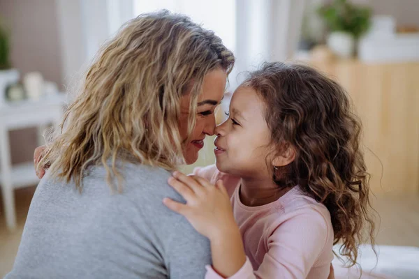 Primer plano de madre feliz con su pequeña hija abrazándose y mirándose en casa. —  Fotos de Stock
