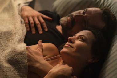 Üzgün, olgun bir adam karısını aldattığı için kendini suçlu hissederken karısı ona sarılıyor..