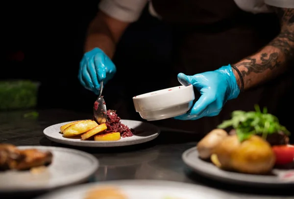 Chefs hands in gloves serving and decorating meal in restaurant kitchen — Stock Photo, Image
