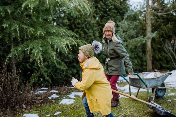 Pojke med Down syndrom med sin mormor arbetar i trädgården på vintern tillsammans. — Stockfoto