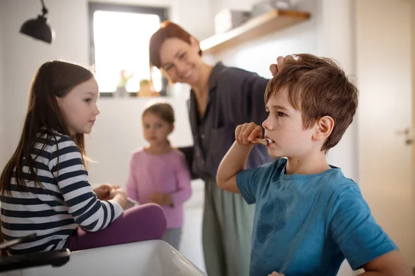 Mother with three little children in bathroom, brushing teeth. — Stock Photo, Image