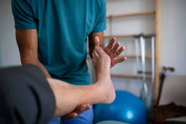 Primer plano del fisioterapeuta haciendo ejercicio con la pierna de los pacientes mayores en una sala física. — Foto de Stock