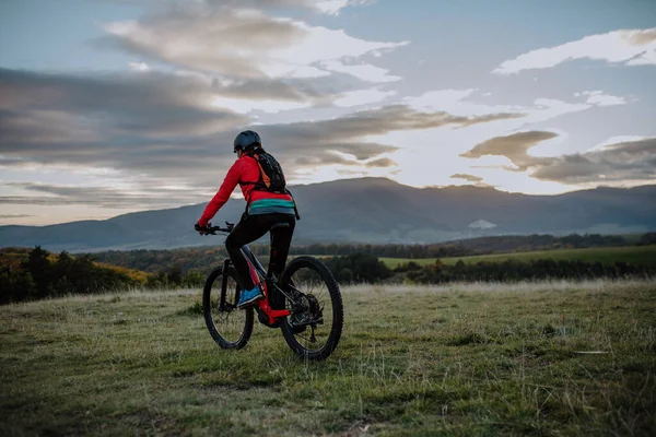 Bakifrån av aktiv senior kvinna cyklist ridning cykel i naturen på höstdagen. — Stockfoto