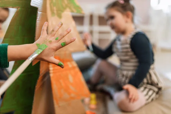 Nahaufnahme eines kleinen Mädchens beim Malen mit dem Pinsel auf der Hand während des Kunstunterrichts. — Stockfoto