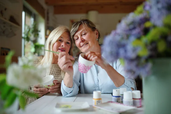 Felice artista donna anziana che insegna al suo amico come dipingere tazza cermaic, concetto di arte. — Foto Stock