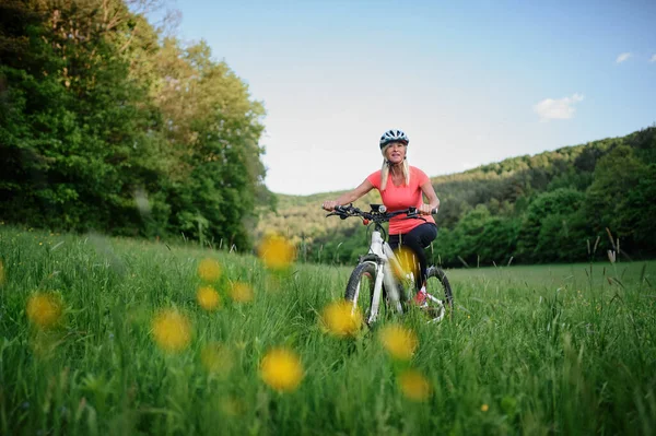 Wesoły aktywny starszy kobieta rowerzysta jazda na rowerze na świeżym powietrzu w przyrodzie. — Zdjęcie stockowe