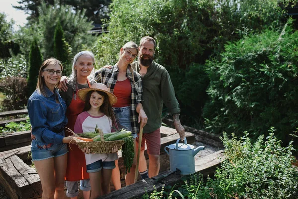 Happy farmer family looking at camera and holding their harvest outdoors in garden. — Stock Photo, Image