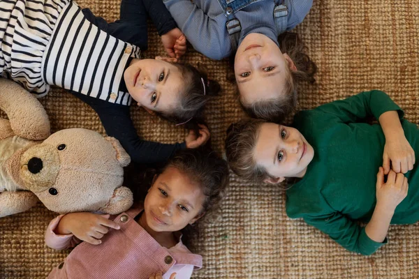 Top view of of little girls friends lying on back on floor and looking at camera. — Stock Photo, Image
