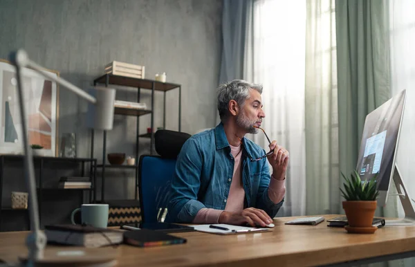 Volwassen man architect werkt op de computer aan het bureau binnen in het kantoor. — Stockfoto