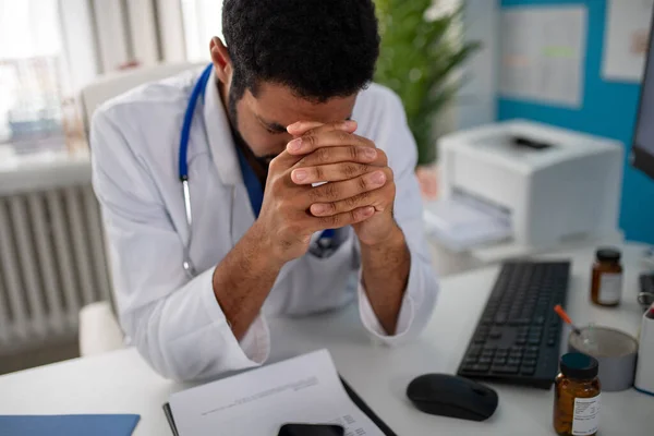 Depressieve jonge mannelijke arts met hoofdpijn in zijn kantoor — Stockfoto