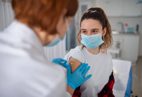 Mujer joven que recibe la vacuna covid-19 del médico en la clínica. — Foto de Stock