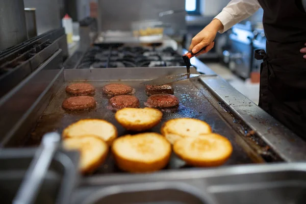 Primo piano di chef professionista che prepara hamburger al chiuso nella cucina del ristorante. — Foto Stock