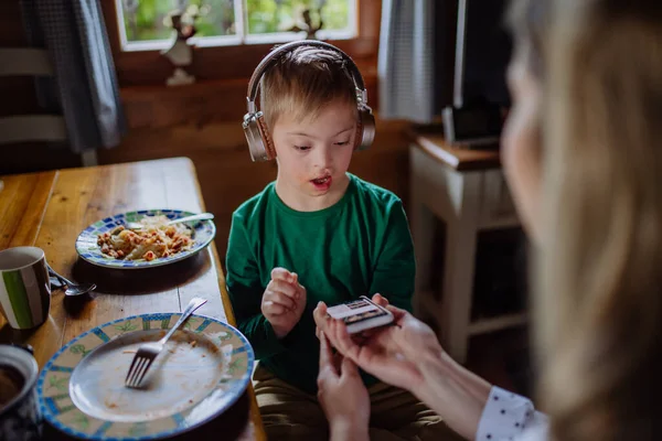 Niño con síndrome de Down con su madre almorzando y usando smartphone en casa — Foto de Stock