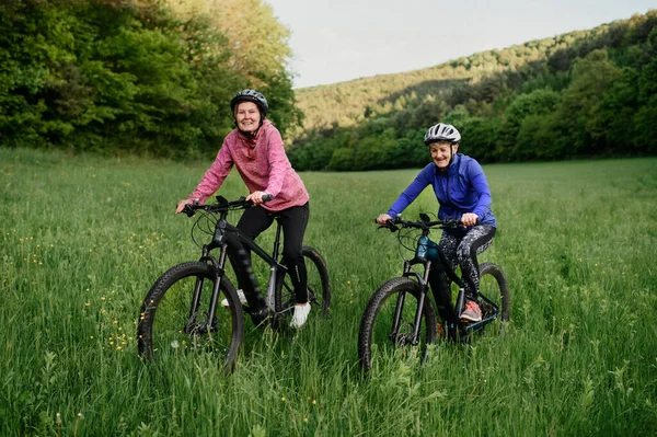 Glada aktiva äldre kvinnor vänner cykla tillsammans utomhus i naturen. — Stockfoto