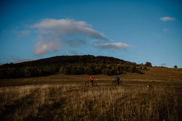 Widok boczny aktywnej pary jazdy na rowerach w lesie jesienią. — Zdjęcie stockowe