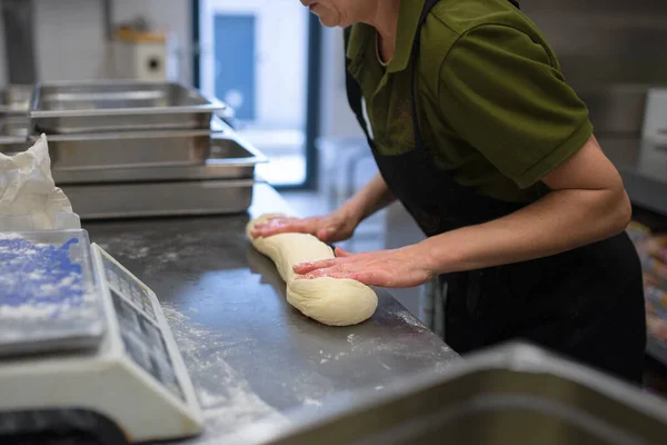 Неузнаваемый шеф-повар месит дрожжевое тесто в помещении на кухне ресторана. — стоковое фото