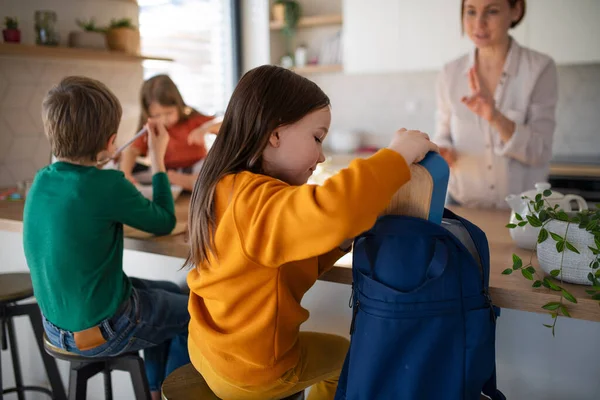 Pequeña niña embalaje almuerzo caja para mochila en la cocina en casa. — Foto de Stock