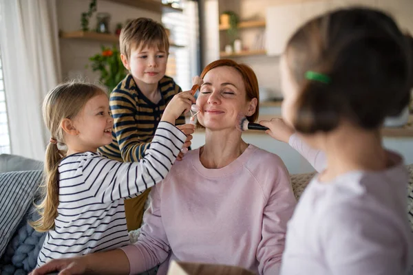 Tres niños pequeños haciendo masaje y apllying hacen las paces a su madre en casa. —  Fotos de Stock
