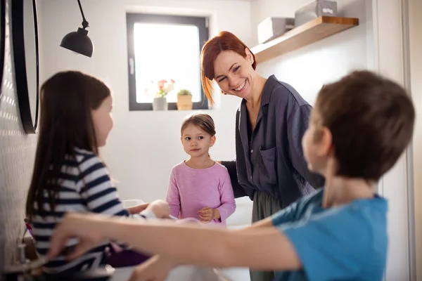 Mutter mit drei kleinen Kindern im Badezimmer, Konzept der Morgenroutine. — Stockfoto