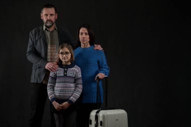 Tek çocuklu mülteci ailesi siyah arka planda kameraya bakıyor, Ukrayna savaş konsepti.