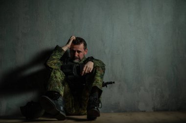 Hayal kırıklığına uğramış asker kampta tek başına oturup ağlıyor..