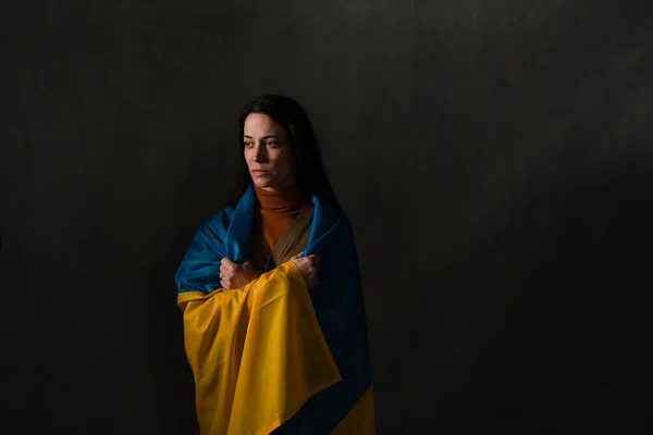 Сумна жінка покрита прапором України. Концепція бути з українським народом у війні з Росією. — стокове фото