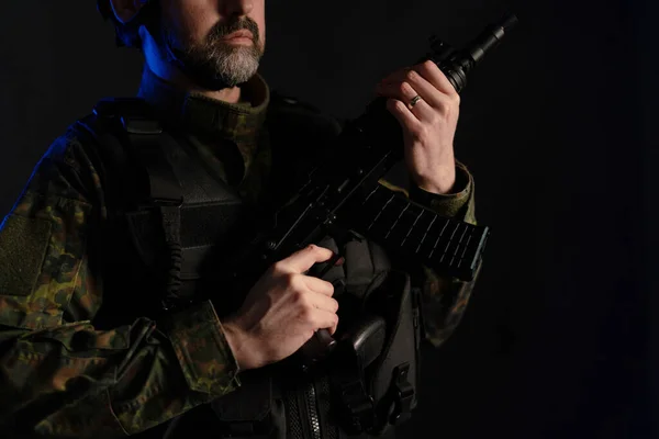 Primer plano del soldado en uniforme militar con arma sobre fondo negro. — Foto de Stock