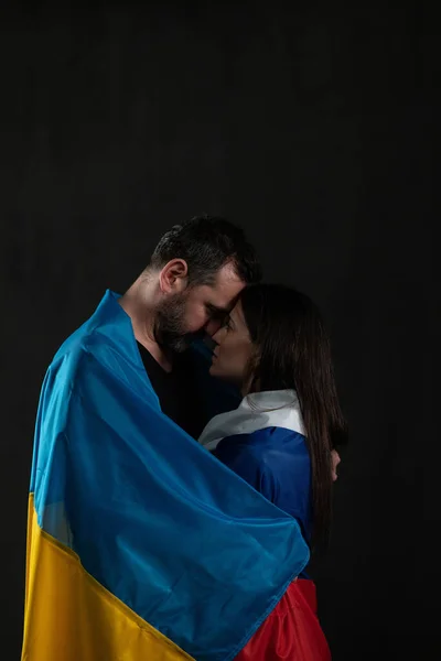 Man in Ukraine flag and woman in Russian flag in love hugging, cross-border love concept. — Fotografia de Stock