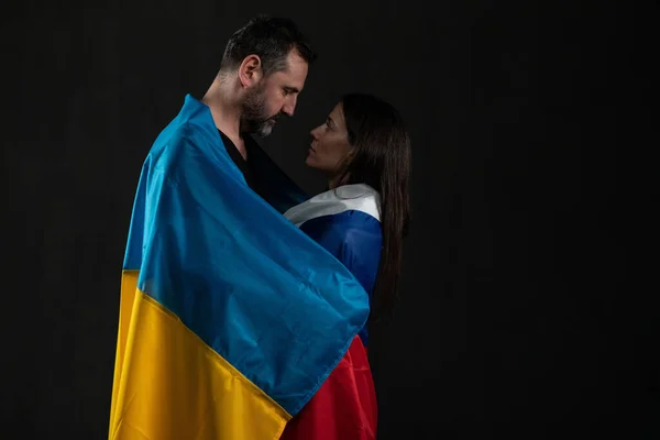 Hombre en Ucrania bandera y mujer en bandera rusa en el amor abrazo, concepto de amor transfronterizo. — Foto de Stock