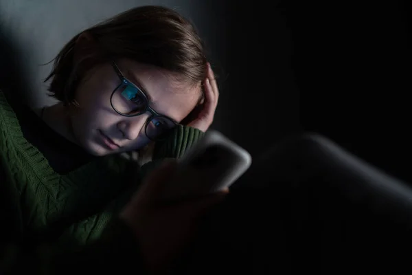 Menina triste, sozinho na escuridão, sentado e usando smartphone. — Fotografia de Stock