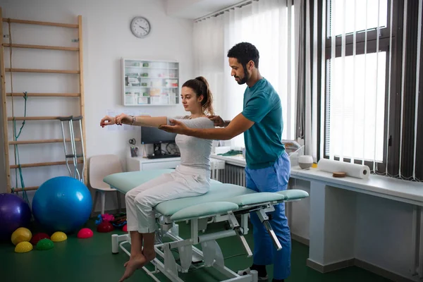 Giovane fisioterapista maschile visita giovane paziente donna in una stanza fisica — Foto Stock