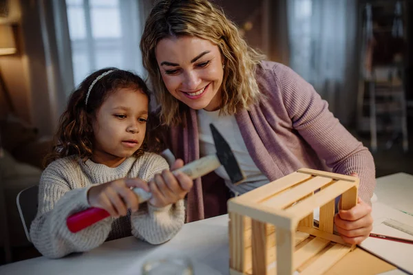 Felice bambina ristrutturare una cassa di legno insieme a sua madre a casa. — Foto Stock