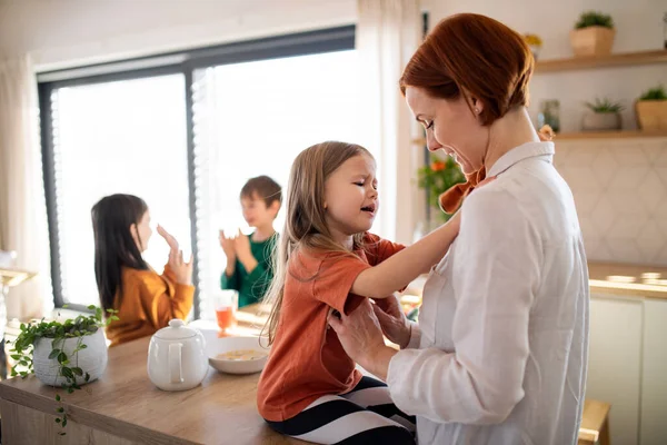 Madre abrazando a su hija pequeña en la cocina en casa. —  Fotos de Stock