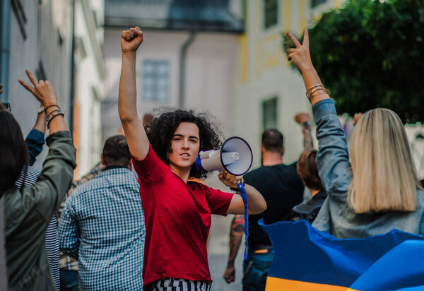 Crowd of activists protesting against Russian military invasion in Ukraine walking in street.