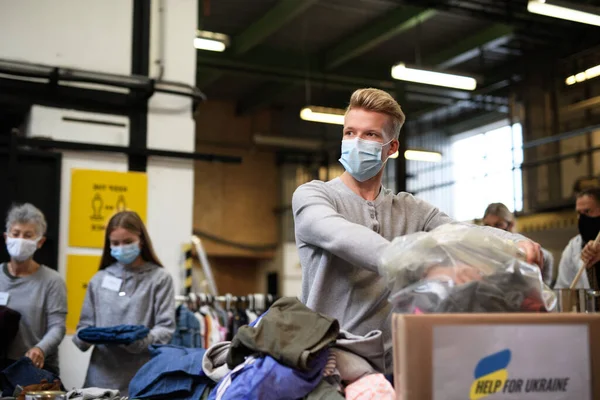 Volontaires tri des vêtements donnés pour les besoins des migrants ukrainiens, concept d'aide humanitaire. — Photo