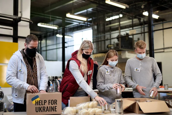 Добровольцы сортируют пожертвованные продукты питания для нужд украинских мигрантов, концепция гуманитарной помощи. — стоковое фото