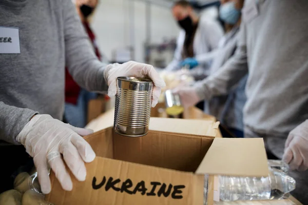 Group of volunteers collect donations for Ukrainian refugees, humanitarian aid concept.