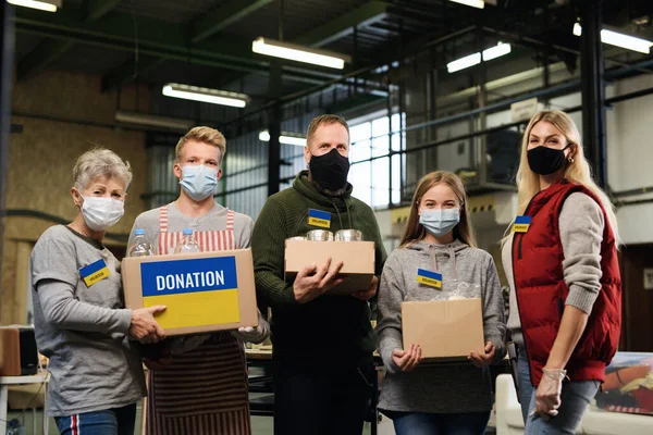 Grupp av volontärer hjälpa i ukrainska flyktingcentrum tittar på kameran, ryska konflikt koncept. — Stockfoto