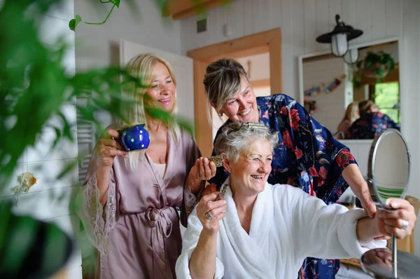 Boldog idősebb nők barátok fürdőköpenyben szórakozás beltéri fürdőszobában, önellátás koncepció. — Stock Fotó