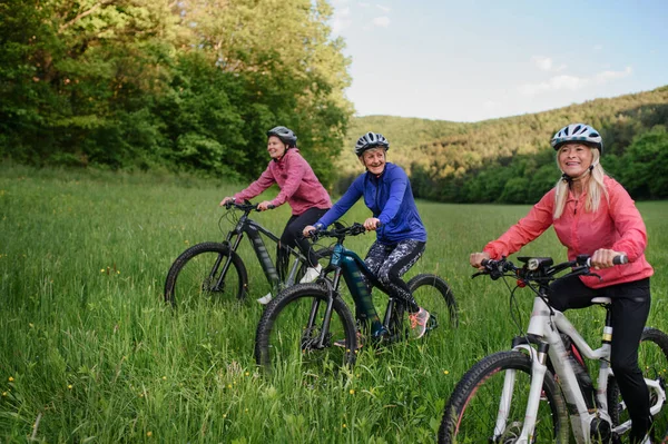 Szczęśliwy aktywny starszy kobiety przyjaciele jazda na rowerze razem na świeżym powietrzu w przyrodzie. — Zdjęcie stockowe