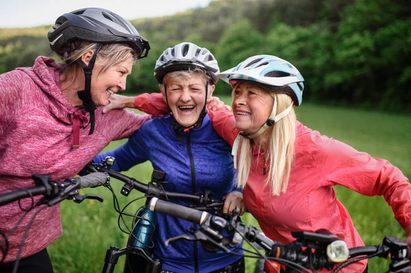 Glückliche aktive Seniorinnen radeln gemeinsam in der Natur. — Stockfoto
