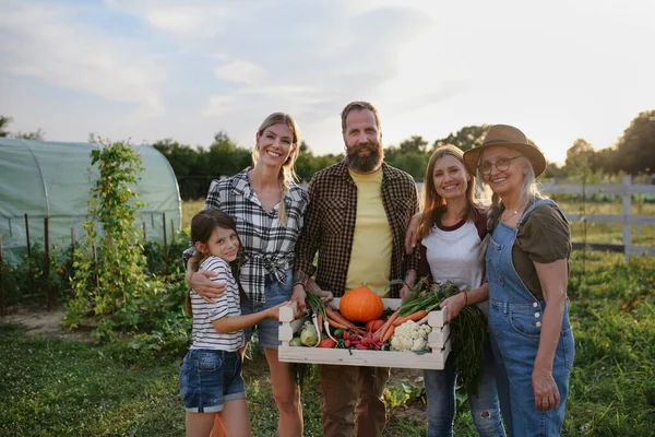 幸せな農家の家族はカメラを見て、庭で屋外で収穫を保持します. — ストック写真
