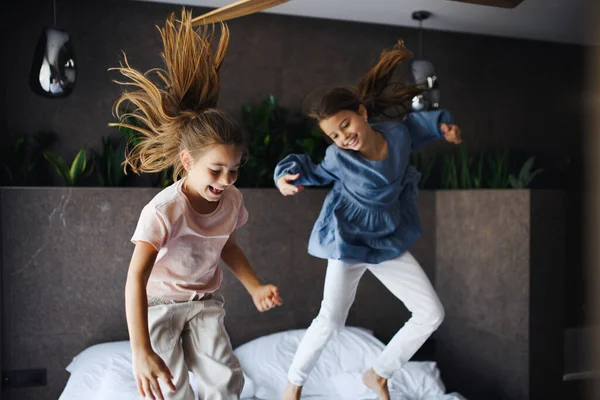 Due sorelline che saltano sul letto all'interno dell'hotel. — Foto Stock