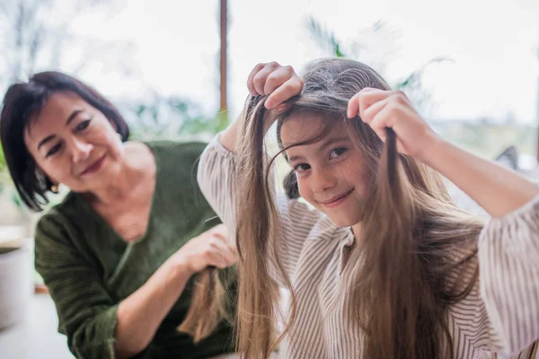 Avó ajudando sua neta com fazer um penteado. — Fotografia de Stock