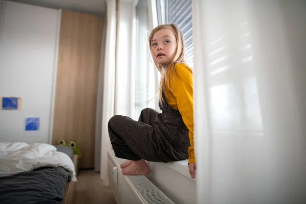 Triste petite fille avec le syndrome de Down assis sur la fenêtre à la maison. — Photo